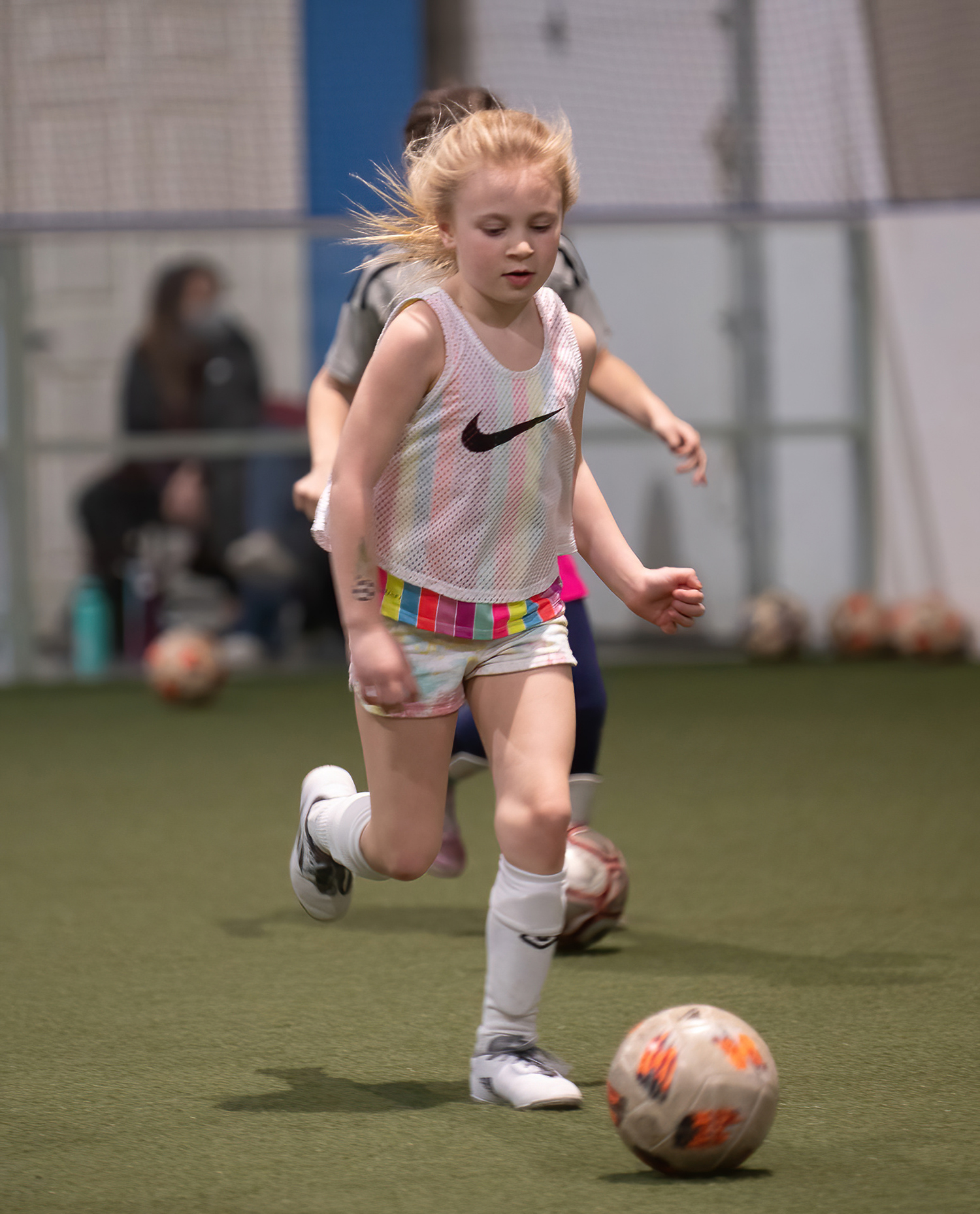 young lady in a white nike jersey dribbles a soccer ball