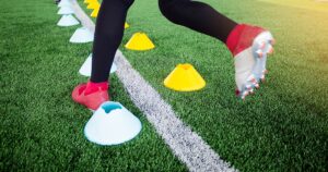 Close-up of a soccer player's feet performing footwork drills through cones during a training session.