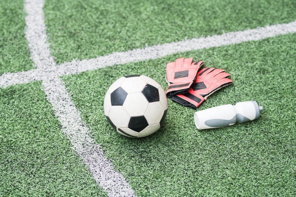 Close-up of a soccer ball, goalie gloves, and a water bottle on an indoor turf field at Locker Soccer Academy in Powell, Ohio.