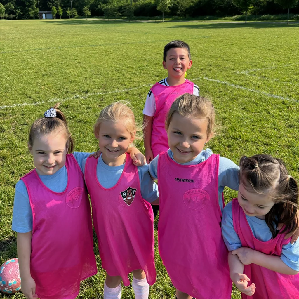 Campers wearing bright pink pinnies smile and have fun during Locker Soccer Academy summer camp