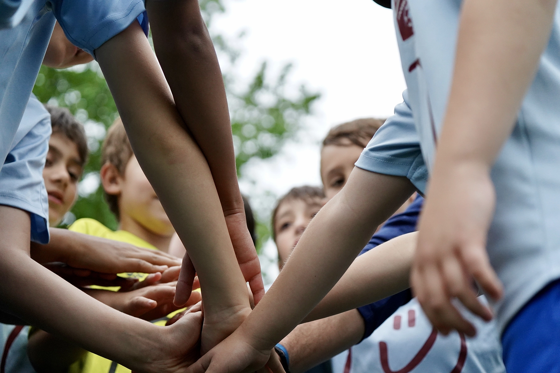 Young soccer campers stacking hands together during a team huddle at Locker Soccer Academy summer camp
