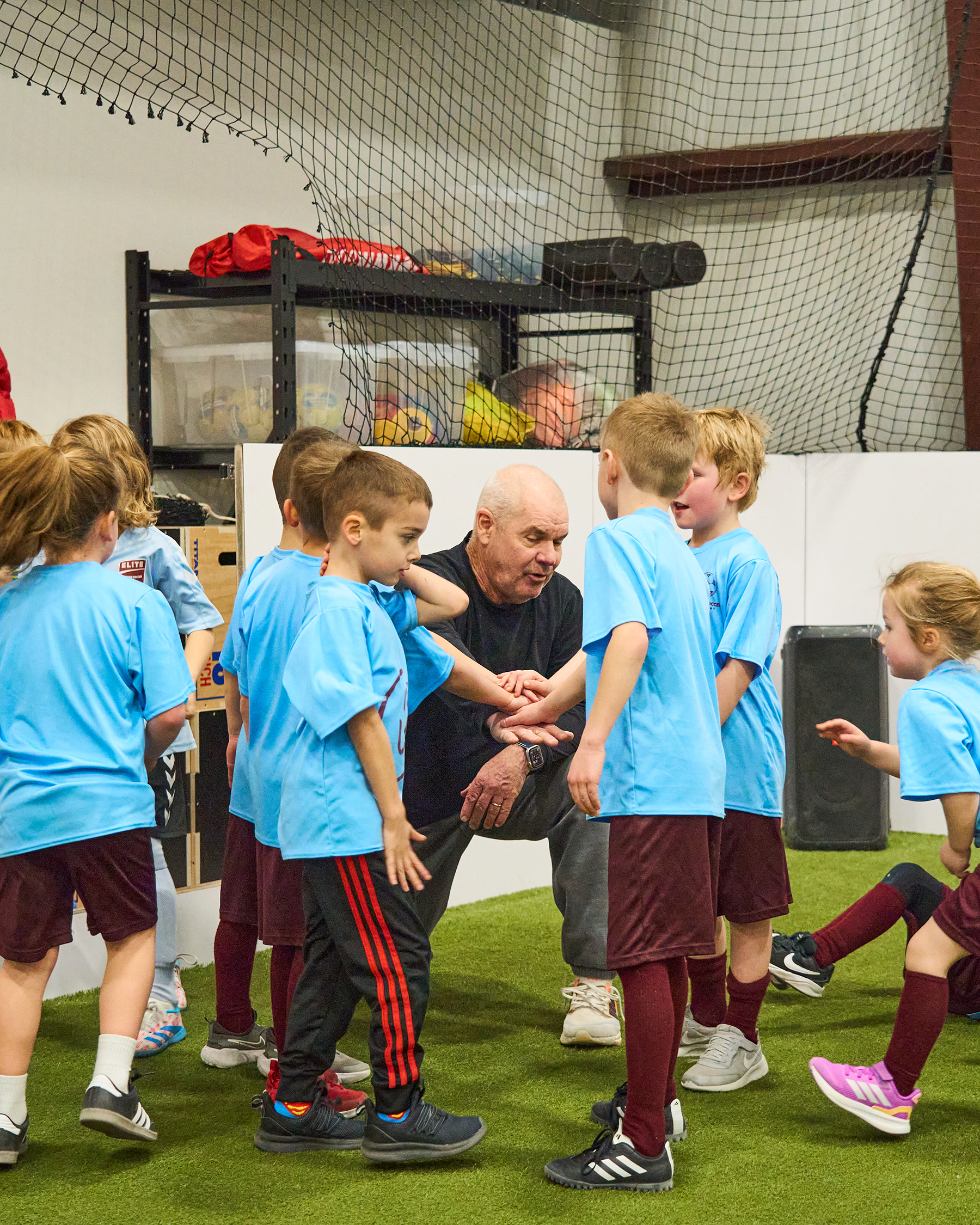 Youth soccer players in team huddle with coach Steve Locker before scrimmage